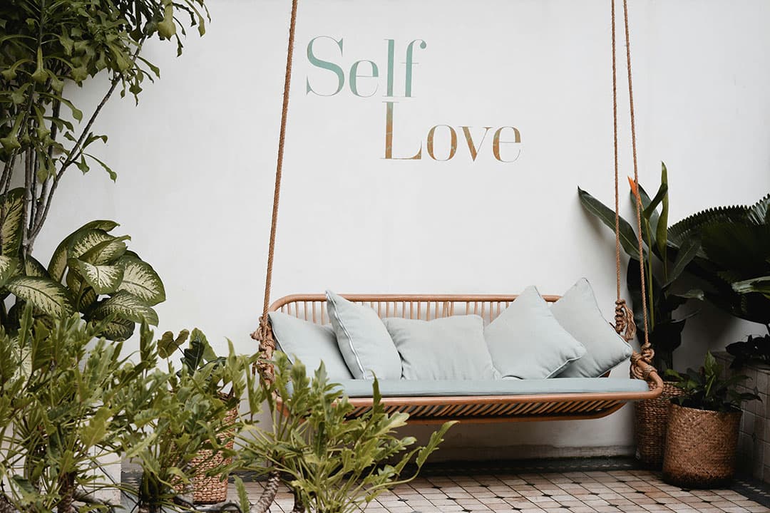 Hanging sofa with self love signage above it